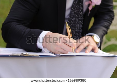 groom signing marriage certificate with golden pen