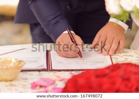 groom signing certificate in red folder