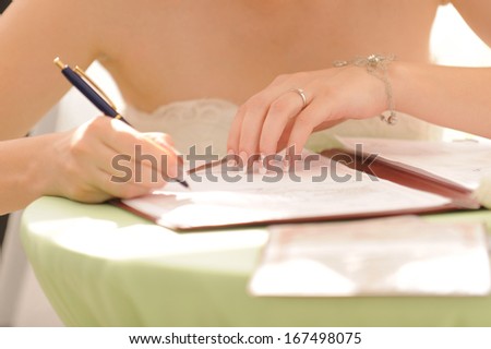 bride with elegant manicure signing certificate