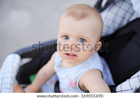scared little girl sitting in baby carriage