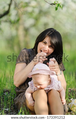 mother biting her laughing daughter\'s foot