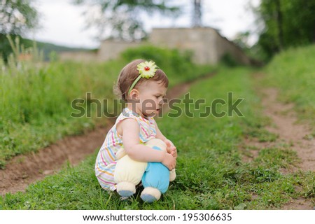 pensive girl sitting on path with toy