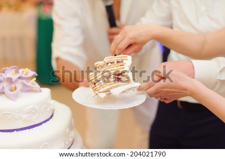 bride and groom holding slice of wedding cake