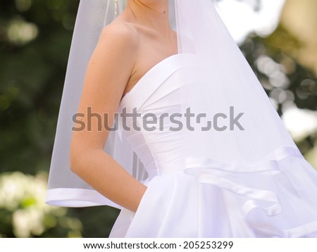 bride in sating dress holding hand in pocket