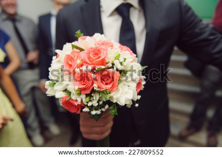 groom holding rose wedding bouquet