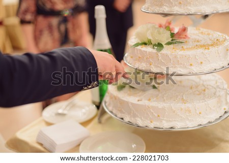 groom holding knife cutting cake