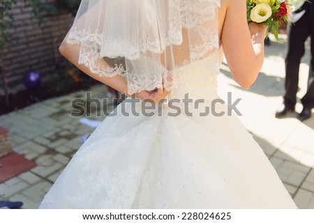 bride zipping her wedding dress in yard