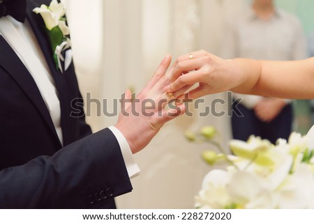 bride putting on wedding ring on groom\'s finger