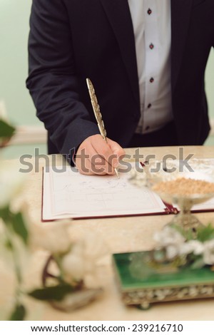 groom signing contract with metal feather