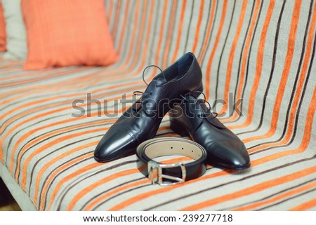 black shoes and belt on striped bed
