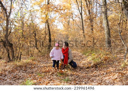 mother and baby picking dry leaves up in forest