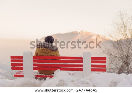 man on bench enjoying view on mountain at sunset
