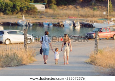 family is walking along river at sunset