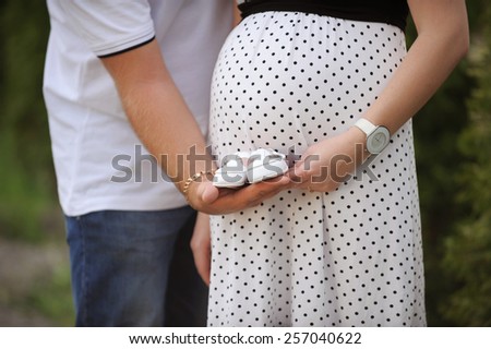 man holding kid's shoes at woman's belly