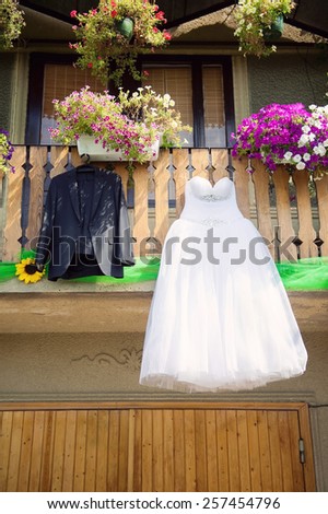 bride\'s dress and groom\'s suit hanging in yard