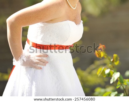 bride with freckles in wedding dress with red ribbon