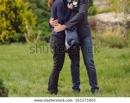 hugging couple standing on green grass in park