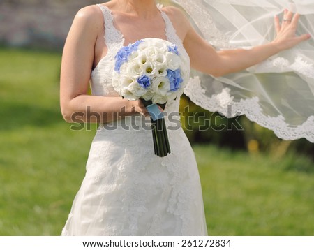 bride holding wedding bouquet and flying veil