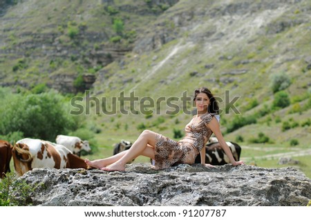 Smiling girl on a stone among cows