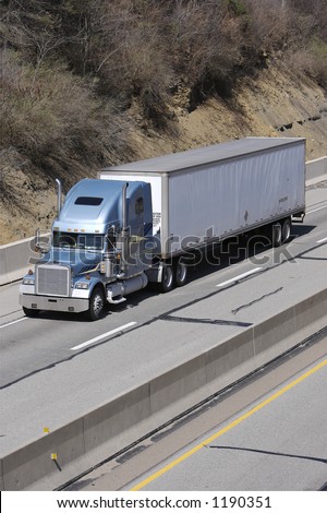 Light Blue Tractor Trailer Truck with White Trailer on the Freeway