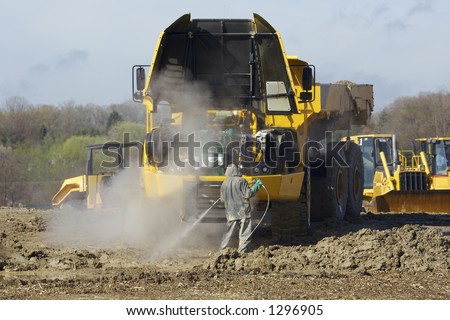 Heavy Dump Truck with Hood up while man is washing engine