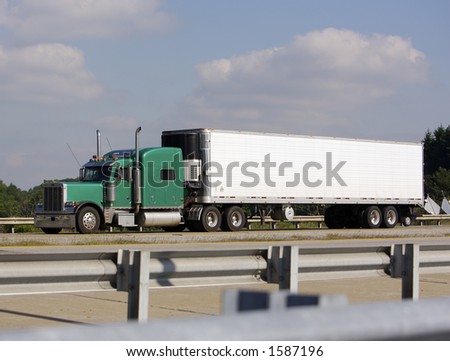 Green Semi Truck on Highway with Guard rail in Foreground