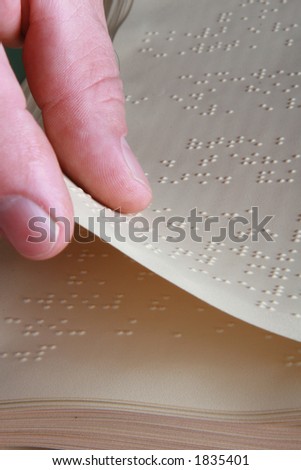 closeup shot of someone turning page on a Braille book