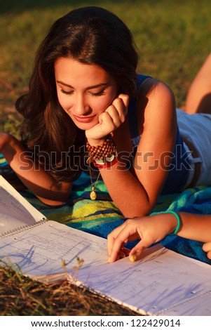 Beautiful multicultural young college woman studying outdoors on campus.