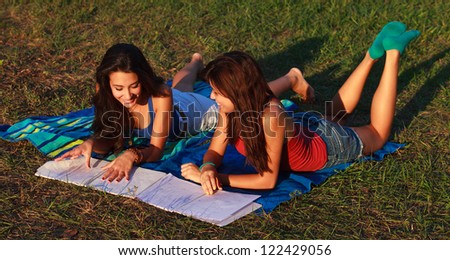 Beautiful multicultural young college women studying outdoors on campus.