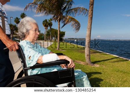 Elderly 80 plus year old woman in a wheel chair convalescing outdoors in a bay setting.