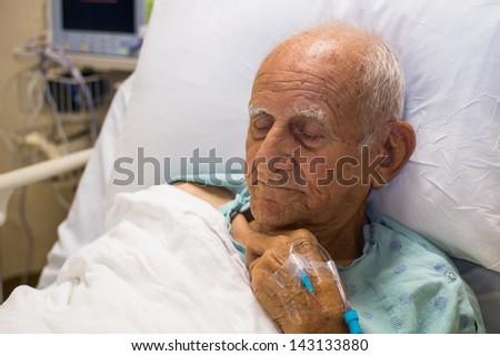 Elderly eighty plus year old man recovering from surgery in a hospital bed.