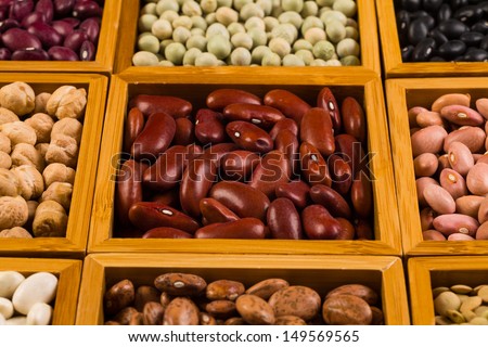 Close up view of a collection of various beans contained in wood boxes.
