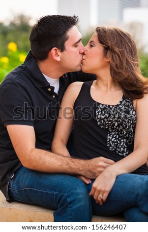 Young couple in a affectionate pose in a urban downtown park  setting at sunset.