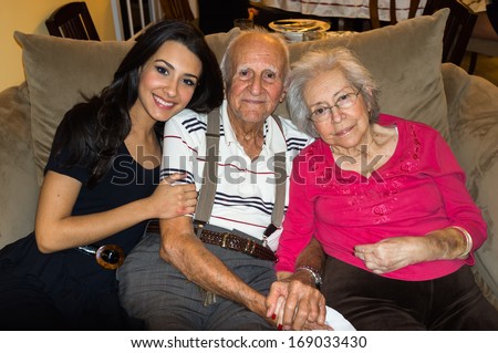 Elderly eighty plus year old grandparents with granddaughter in a home setting.
