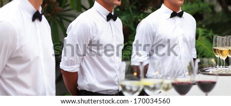 Waiters serving wine at a luxurious gathering.