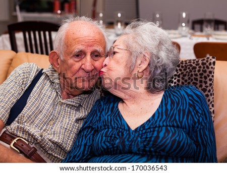 Elderly eighty plus year old couple in an affectionate pose in a home setting.