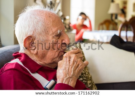 Elderly eighty plus year old man drinking espresso coffee in a home setting.