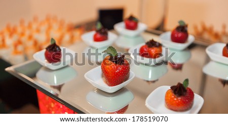 Close up view of a fancy strawberry dessert with dark chocolate topping and mint leaf.