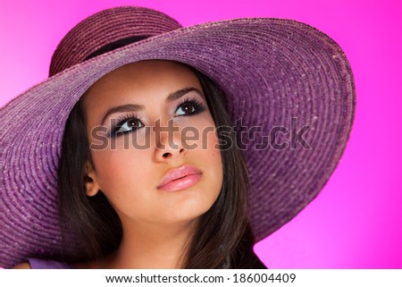 Beautiful young woman wearing a purple hat on a purple background.