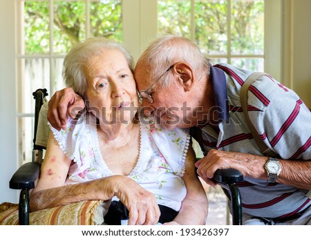 Elderly eighty plus year old woman in a wheel chair in a home setting with her husband.