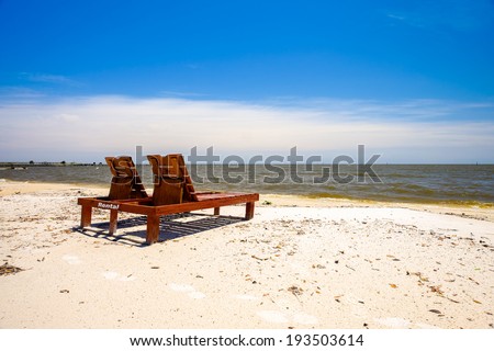 Gulf coast beach in Biloxi, Mississippi with lounge chairs along the shoreline.