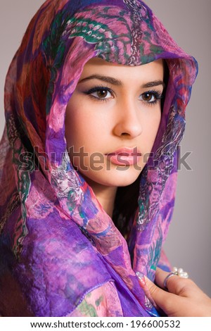 Beautiful multicultural young woman studio portrait wearing a purple veil.