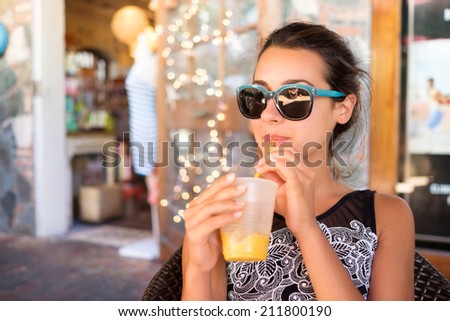 Beautiful girl sipping a smoothie outdoors in a restaurant setting.