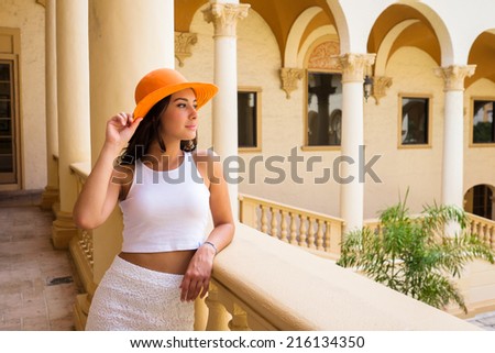 Beautiful young woman wearing a hat in a outdoor courtyard setting.