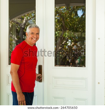 Handsome middle age man opening the door to a residence.