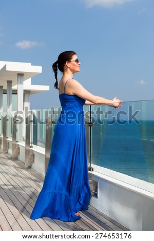 Beautiful middle age woman enjoying the sights of Miami Beach from a balcony.