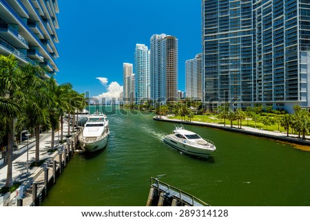 Downtown Miami along the Miami River inlet with Brickell Key in the background and yacht cruising by.