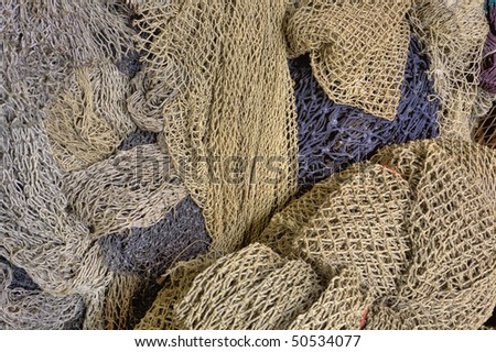 HDR image of a large collection of used fishing nets located near a dock with commercial fishing boats.