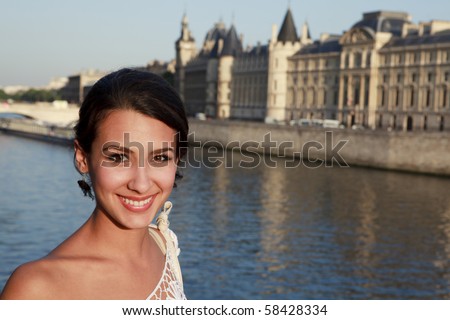 Beautiful young woman on a bridge overlooking the River Seine in Paris, France.