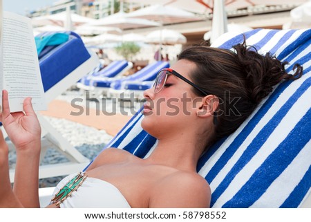 Pretty young woman reading a book while lounging on the French Riviera in Nice, France.